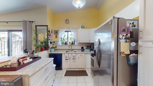 kitchen featuring light tile patterned floors, white cabinets, a sink, stainless steel fridge, and dishwasher