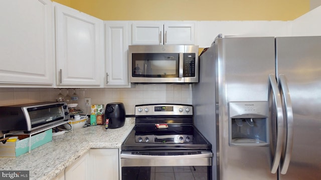 kitchen featuring a toaster, stainless steel appliances, backsplash, white cabinets, and light stone countertops