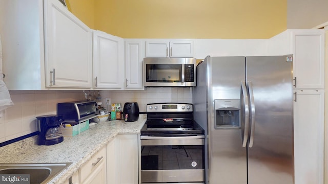 kitchen featuring stainless steel appliances, white cabinetry, and decorative backsplash