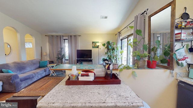 living room featuring arched walkways, a healthy amount of sunlight, visible vents, and wood finished floors