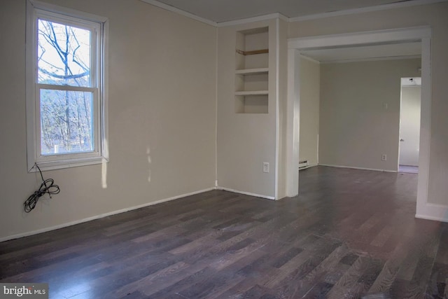 spare room featuring a baseboard heating unit, plenty of natural light, dark wood finished floors, and baseboards