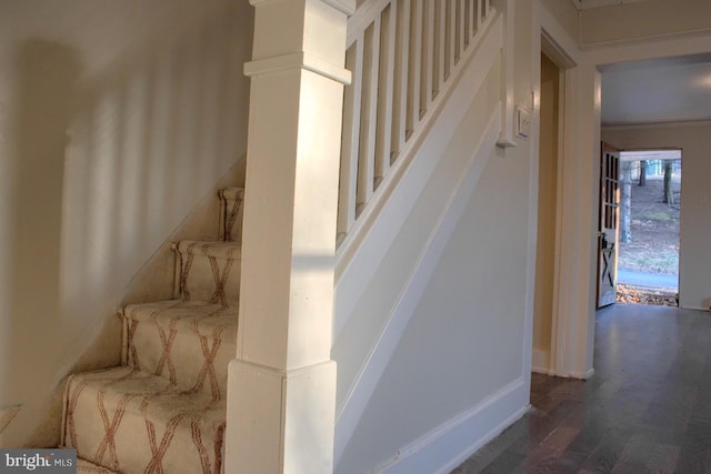 stairs with ornate columns and wood finished floors