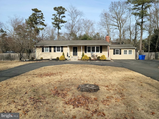 ranch-style home with aphalt driveway, fence, and a chimney