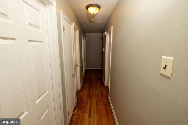 hall with baseboards and dark wood-style flooring