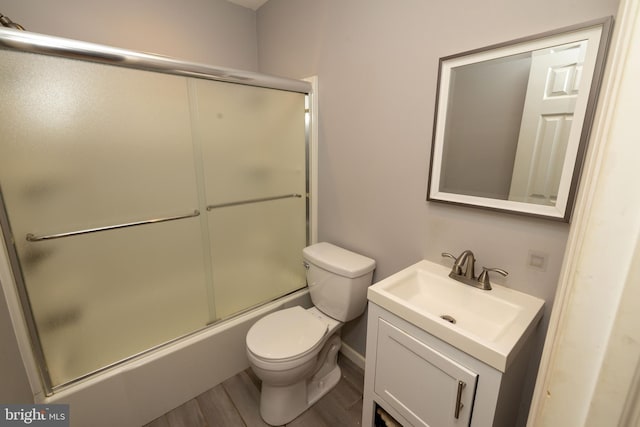 bathroom with vanity, toilet, wood finished floors, and combined bath / shower with glass door