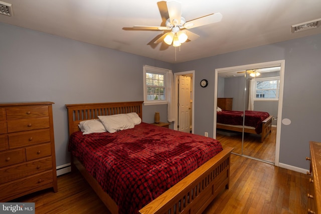 bedroom with visible vents, wood-type flooring, multiple windows, and a closet