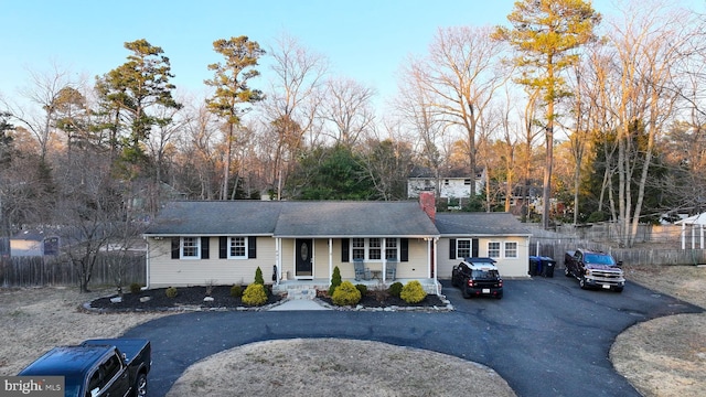 single story home with aphalt driveway, fence, and a chimney