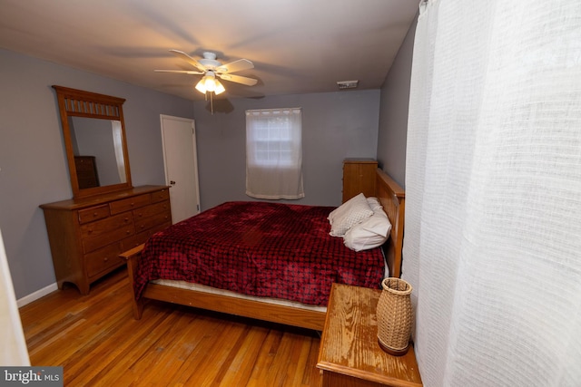 bedroom featuring visible vents, baseboards, ceiling fan, and wood finished floors