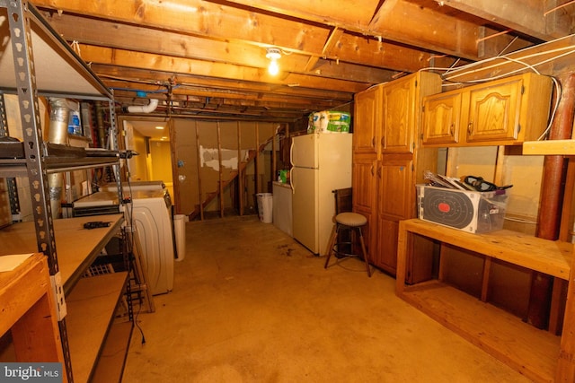 unfinished basement with washer / clothes dryer and freestanding refrigerator