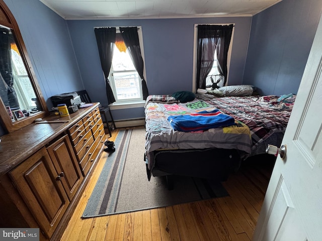 bedroom with light wood-style floors, ornamental molding, and baseboard heating