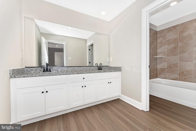 full bath with recessed lighting, a sink, wood finished floors, baseboards, and double vanity