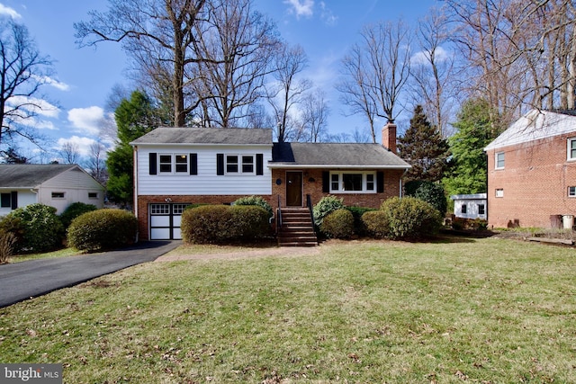 tri-level home featuring brick siding, a chimney, a front yard, a garage, and driveway