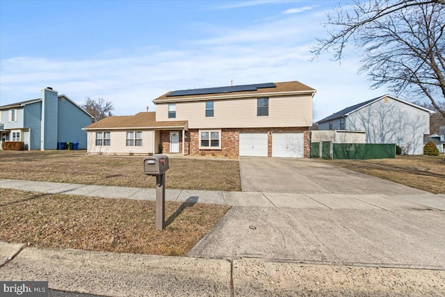 view of front of property featuring an attached garage, roof mounted solar panels, concrete driveway, and brick siding