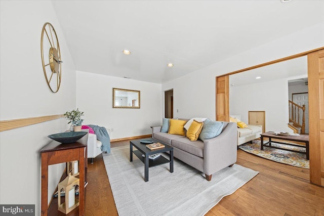 living room featuring stairs, baseboards, wood finished floors, and recessed lighting