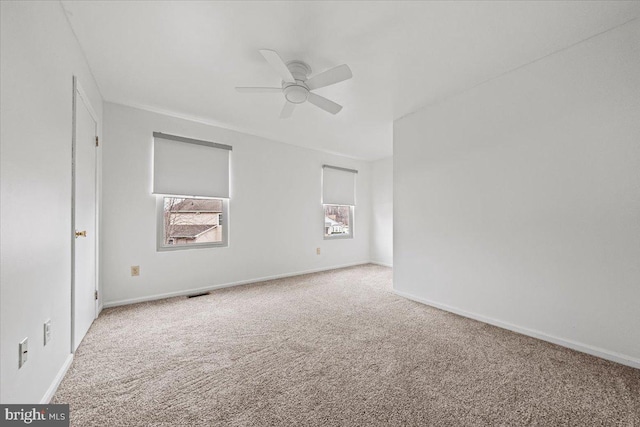 empty room with carpet floors, visible vents, baseboards, and a ceiling fan