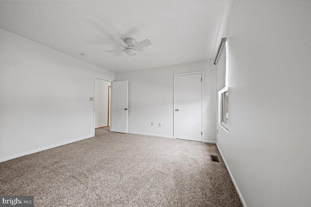 unfurnished bedroom featuring carpet, visible vents, baseboards, and a ceiling fan