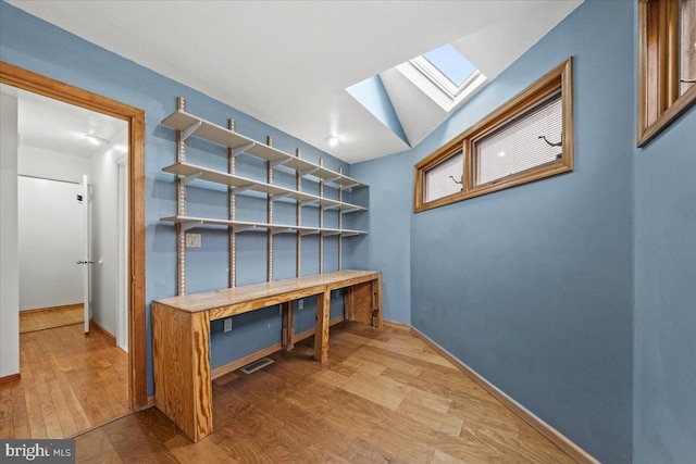 mudroom featuring lofted ceiling with skylight, wood finished floors, and baseboards