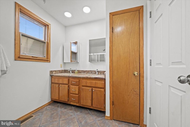 full bath with a sink, visible vents, baseboards, tile patterned floors, and double vanity