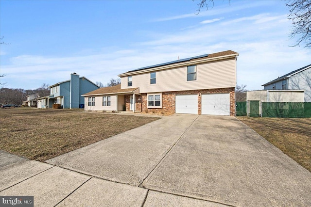 view of front of home with brick siding, solar panels, an attached garage, a front yard, and driveway