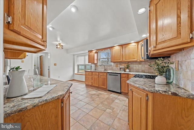 kitchen with baseboards, decorative backsplash, light stone countertops, stainless steel appliances, and a sink