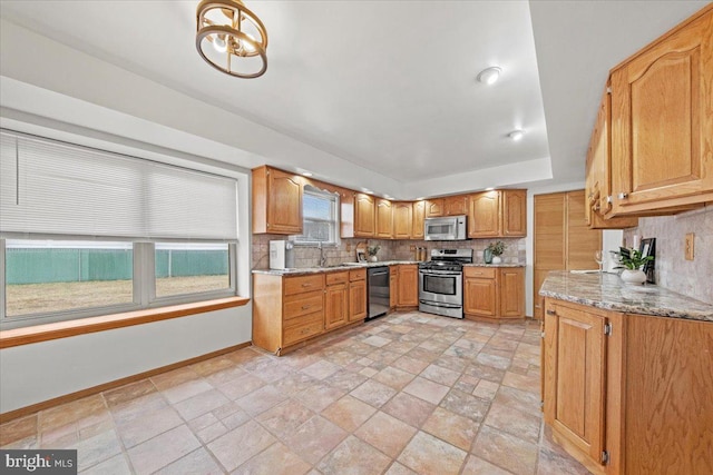 kitchen featuring stainless steel appliances, baseboards, a sink, and decorative backsplash