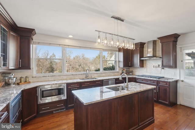 kitchen with a sink, wall chimney exhaust hood, dark wood-style floors, and stainless steel appliances