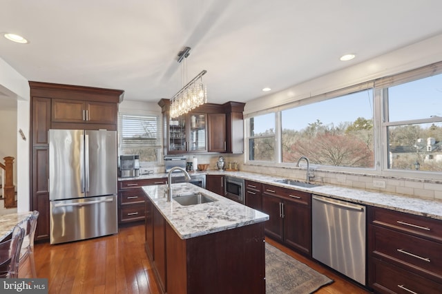 kitchen featuring tasteful backsplash, appliances with stainless steel finishes, a kitchen island with sink, and a sink