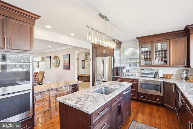 kitchen with dark wood-style floors, decorative backsplash, appliances with stainless steel finishes, and a sink