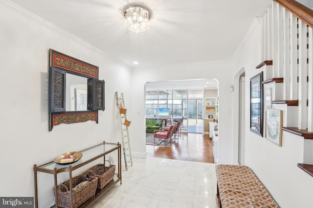 hallway featuring arched walkways, baseboards, crown molding, and an inviting chandelier