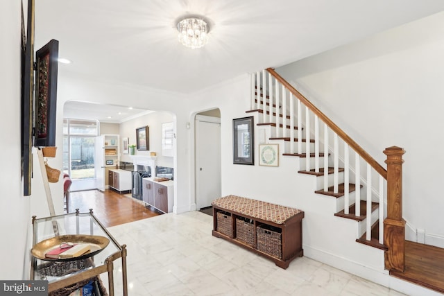 interior space with stairway, baseboards, a fireplace, arched walkways, and ornamental molding