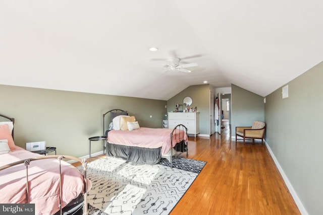 bedroom with a ceiling fan, vaulted ceiling, wood finished floors, and baseboards