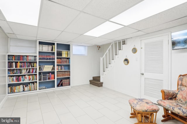 sitting room featuring stairway and a drop ceiling