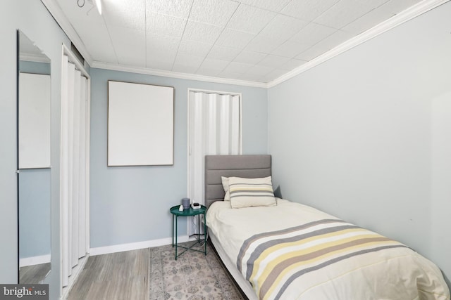 bedroom with crown molding, baseboards, and wood finished floors