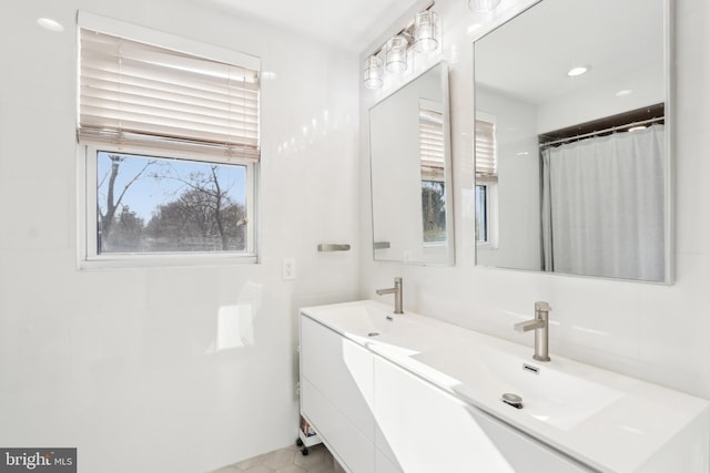 full bathroom featuring double vanity, curtained shower, and a sink