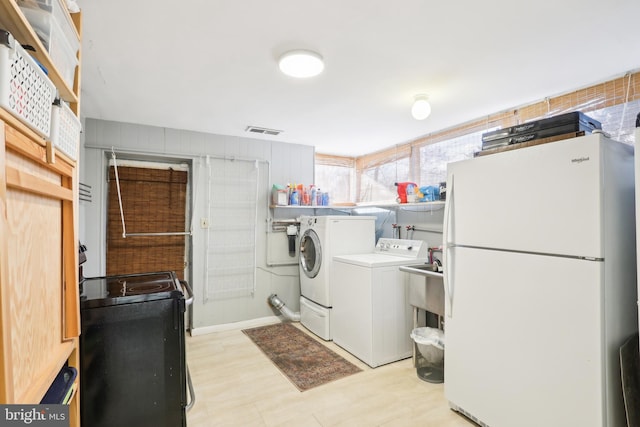 washroom with washer and dryer, visible vents, light floors, and a sink