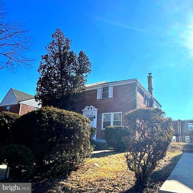 view of front of property with brick siding and a chimney