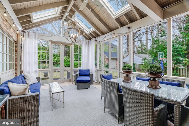 sunroom / solarium featuring vaulted ceiling with skylight and a notable chandelier