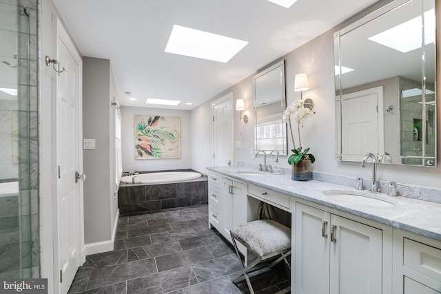 bathroom featuring double vanity, a skylight, a garden tub, and a sink