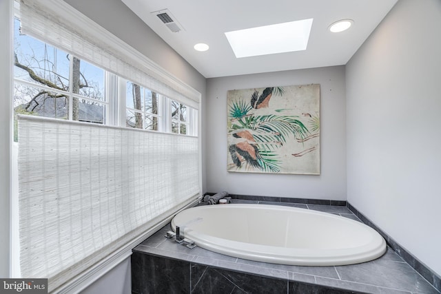 bathroom featuring visible vents, a skylight, and a bath