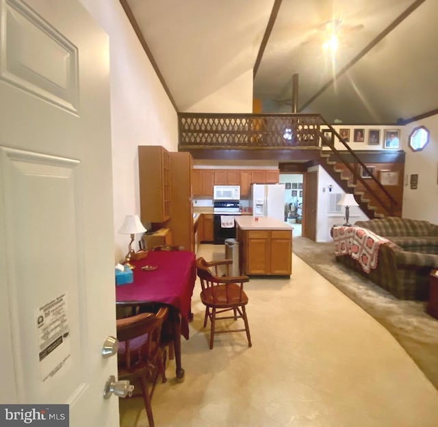 kitchen featuring a center island, light countertops, brown cabinetry, high vaulted ceiling, and white appliances