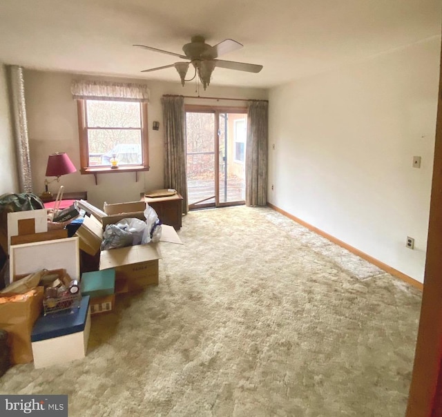 living area with carpet floors, baseboards, and a ceiling fan