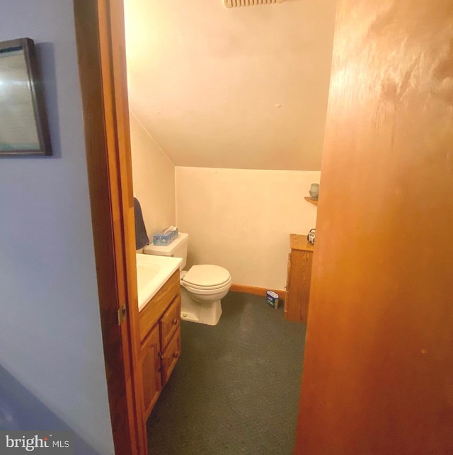 bathroom with lofted ceiling, toilet, vanity, and baseboards