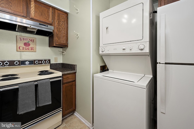 kitchen with brown cabinetry, stacked washer / dryer, white appliances, and under cabinet range hood