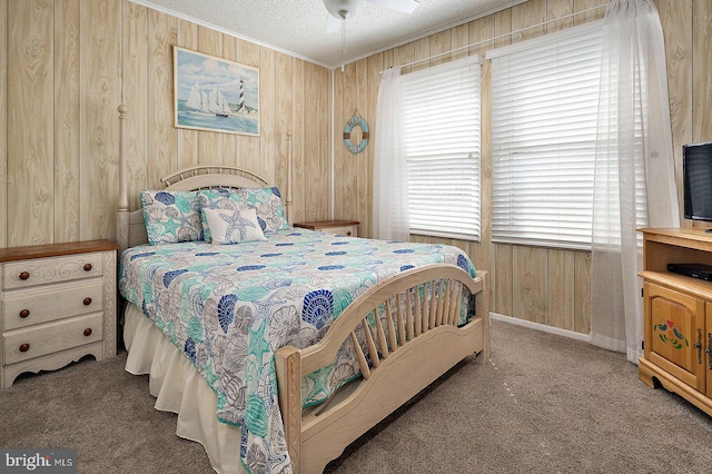 bedroom featuring ornamental molding, carpet, wood walls, and a textured ceiling