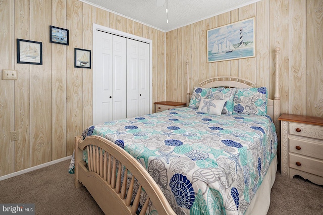 bedroom with a textured ceiling, wood walls, a closet, carpet, and crown molding
