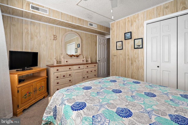 bedroom with wood walls, carpet, visible vents, and a closet