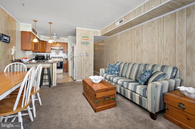 living room featuring ornamental molding, visible vents, and wood walls