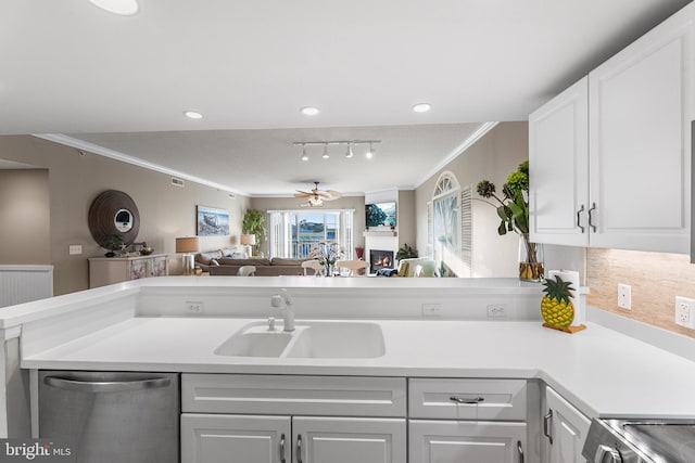 kitchen featuring dishwasher, ornamental molding, open floor plan, light countertops, and a sink