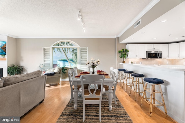 dining space with visible vents, crown molding, and light wood finished floors