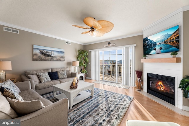 living area featuring visible vents, crown molding, a textured ceiling, and wood finished floors